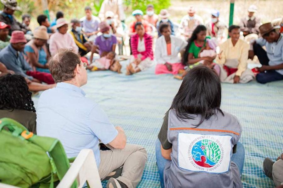 people seated in a big circle on the floor outside, discussing deforestation of Madagascar's rainforests