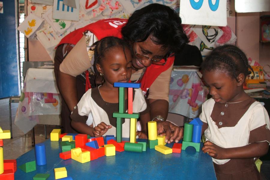 A teacher helping two children with building blocks