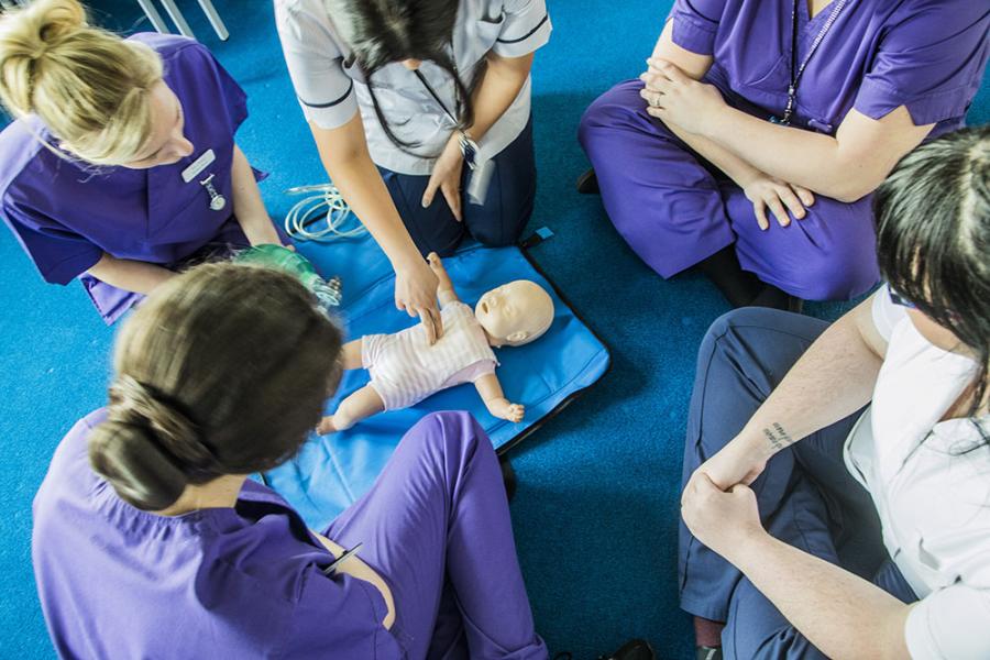 Lecturer with a baby doll, showing students how to perform CPR