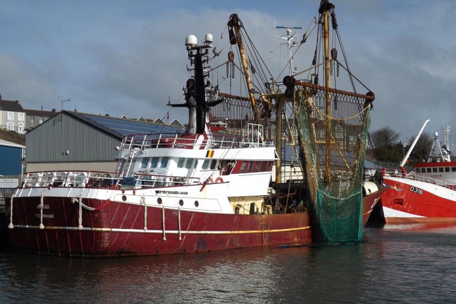 A fishing trawler at the post-side, with nets hanging at side of the boat