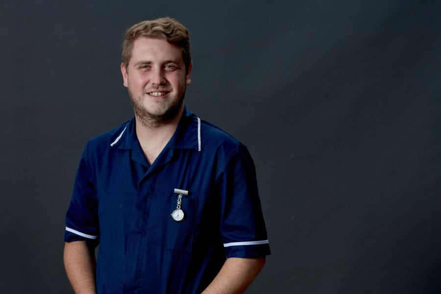 A male midwife in uniform against a grey background