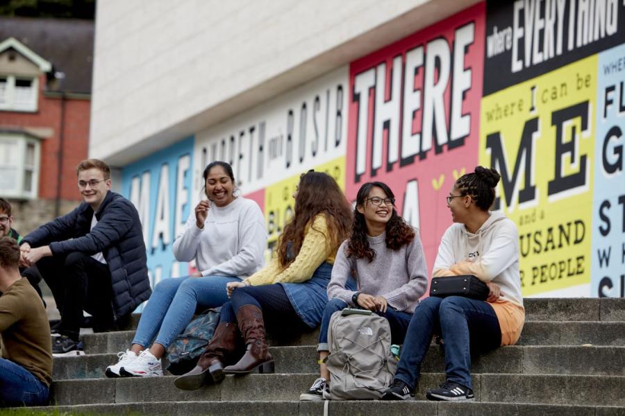 Students sitting on step outside Pontio at Bangor University