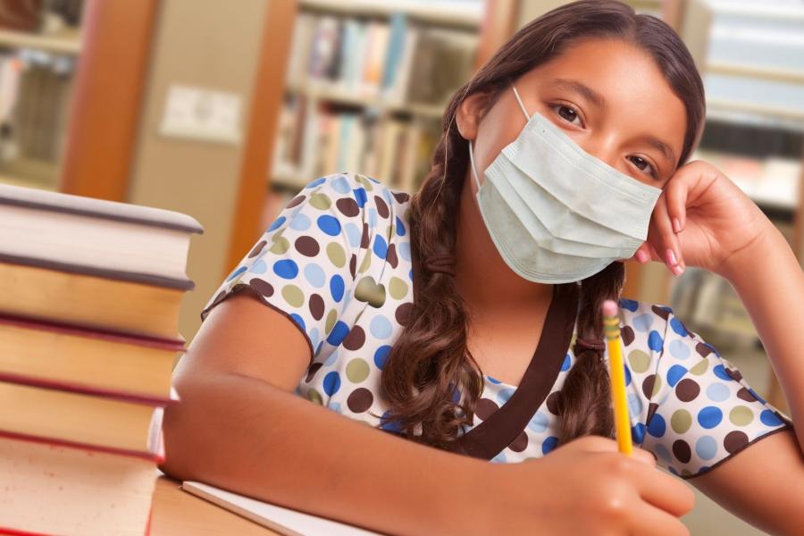 A pupil wearing a Covid mask, sitting by desk.