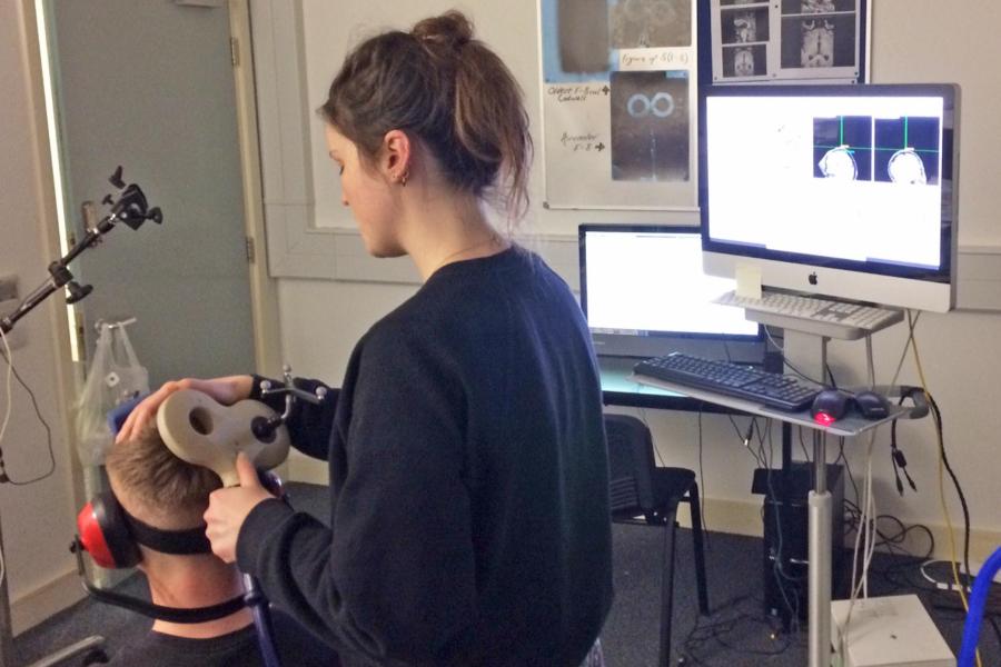 Female using equipment to track brain stimulation on a participant