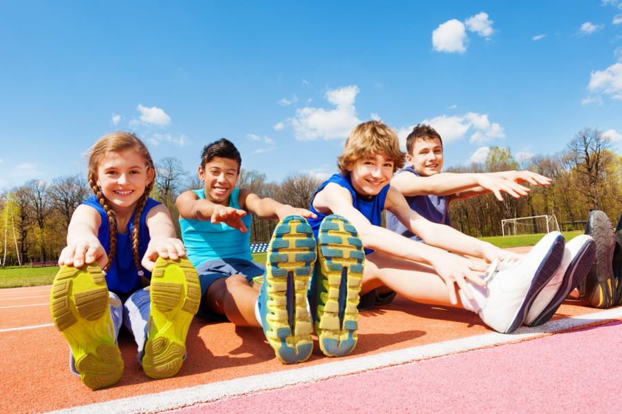 a group of kids streching on a field track 