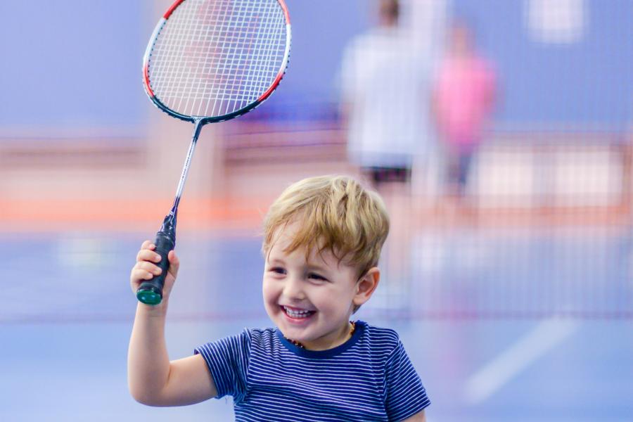 a happy young boy holding a badminton racket