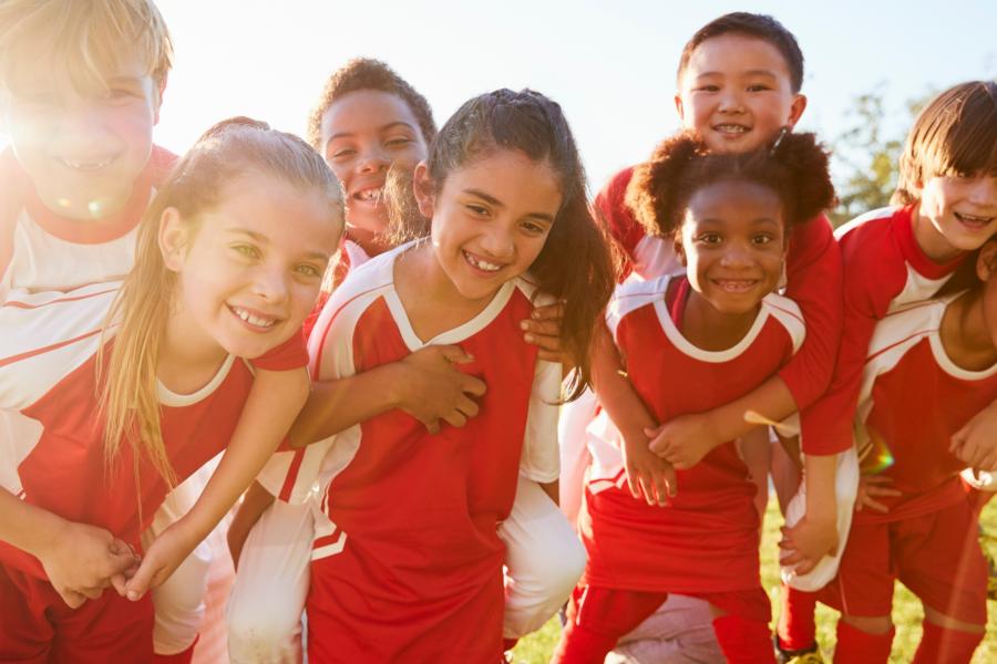 a group of happy children playing football on a sunny day