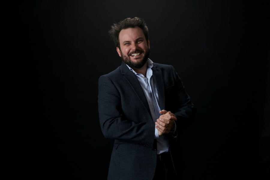 Professor Christian Dunn stands in front of a black background