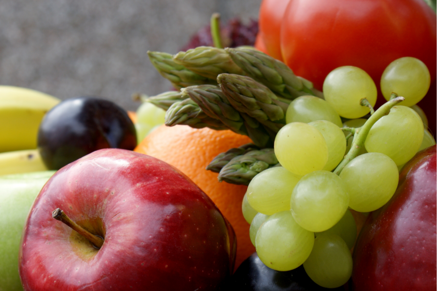 A close up of a bowl of fruit including apples, bananas and grapes