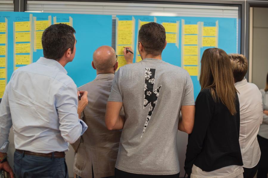 People standing next to wall of sticky notes