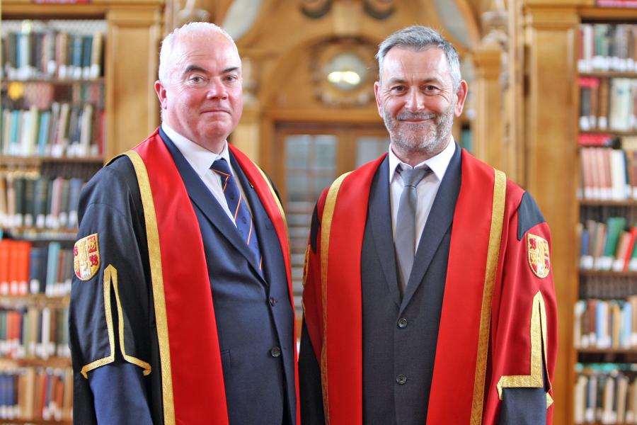 two men in academic gowns in a library
