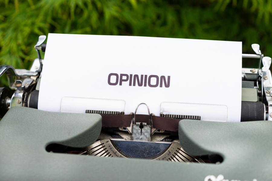 the word opinion is written on a white sheet of paper in a manual typewriter