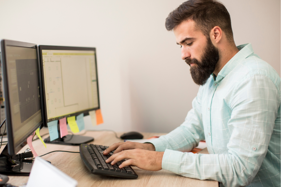 Image of man sitting by his desk working on a pc computer