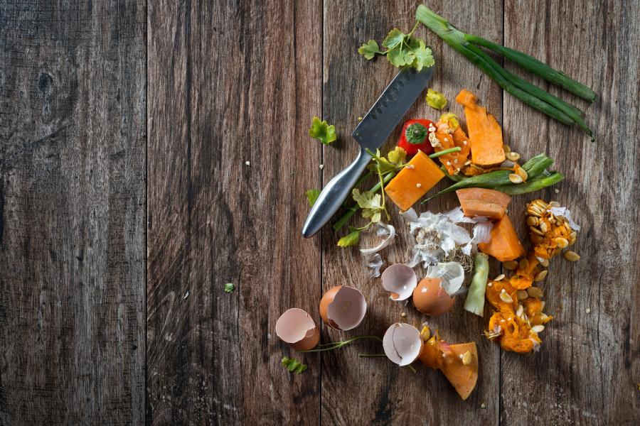 Different food stuff - egg shells, vegetables, seeds on chopping board with chopping knife