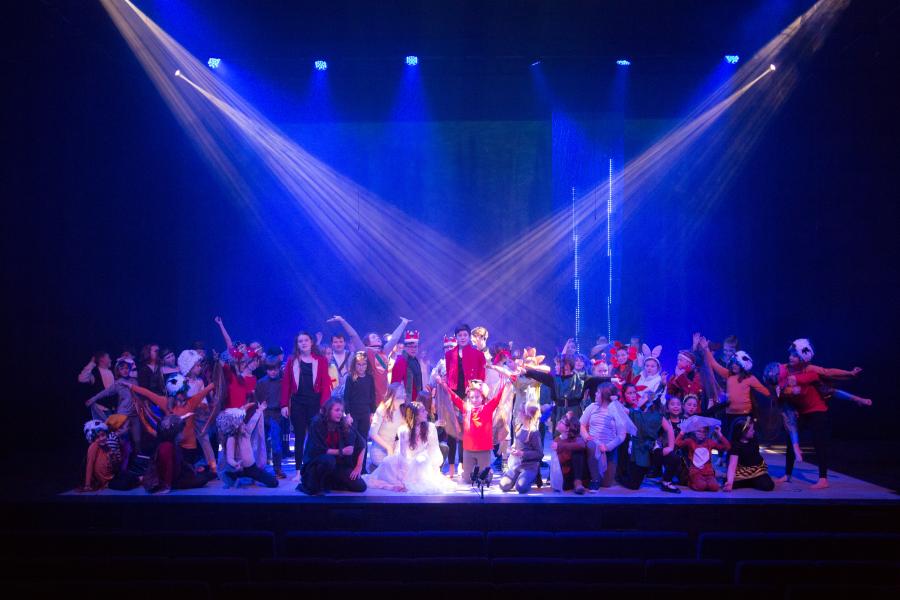 A group of children on stage at the end of a performance at Pontio