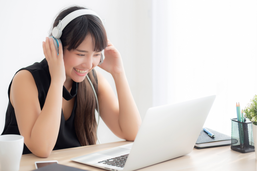 Woman with headphones sitting at a table with her laptop.