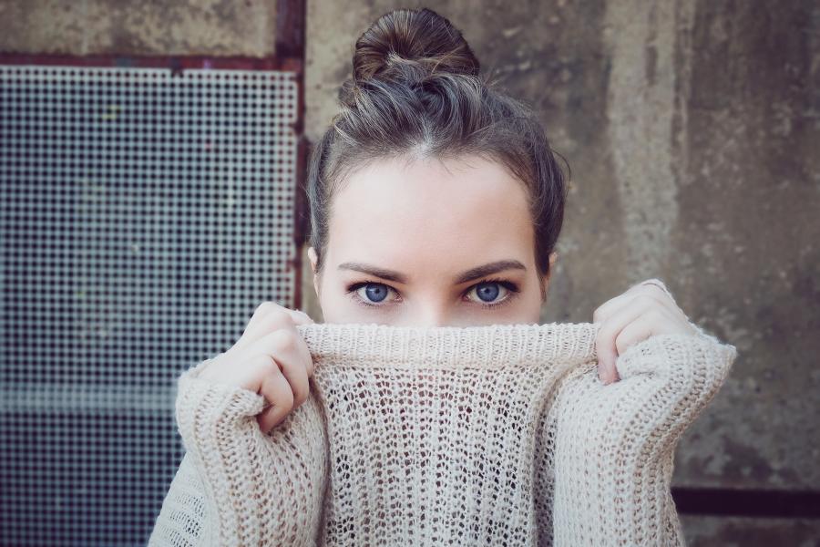 A woman pulls a sweater up to her face