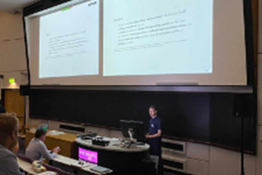 Dr Franck Vidal giving his oral presentation in a lecture room with students with a presentation showing