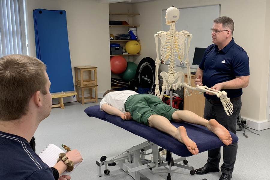 Lecturer Jonathan Flynn in class holding a skeleton during a practical