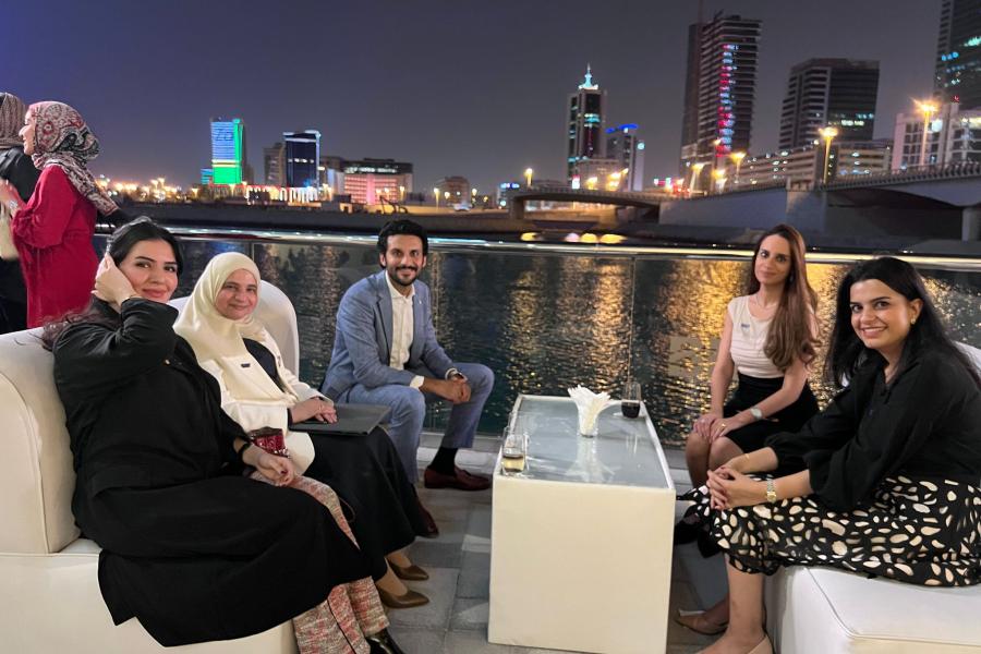 Guests sitting down enjoying the 2022 Bahrain reunion, with Bahrain Bay in the background