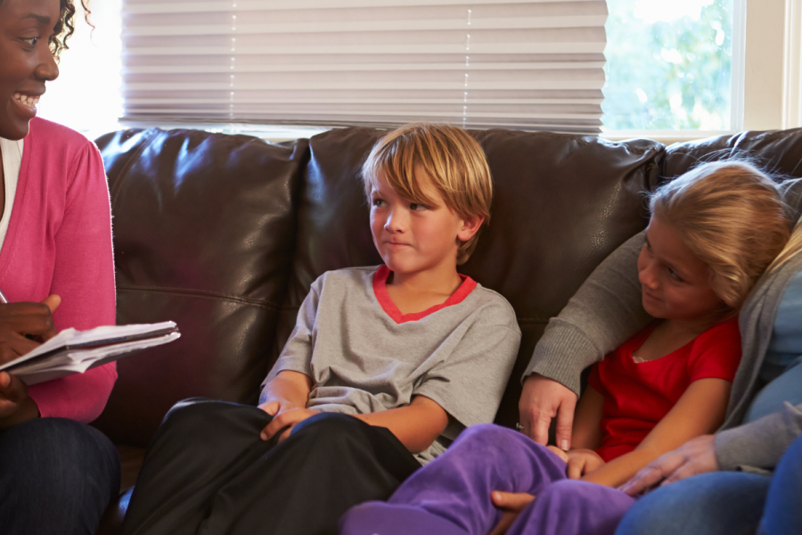 Children sitting on a sofa, smiling at a social worker