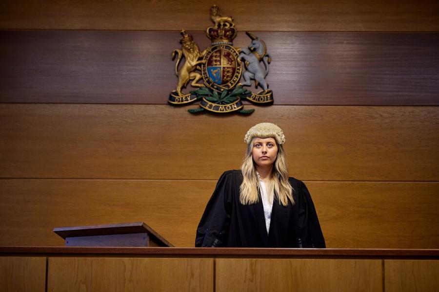 Student looking ahead standing in mock courtroom at Bangor University