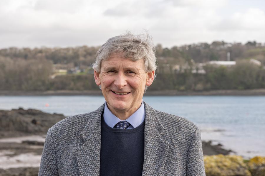 Professor John Turner smiling at the camera on the shore of the Menai Strait