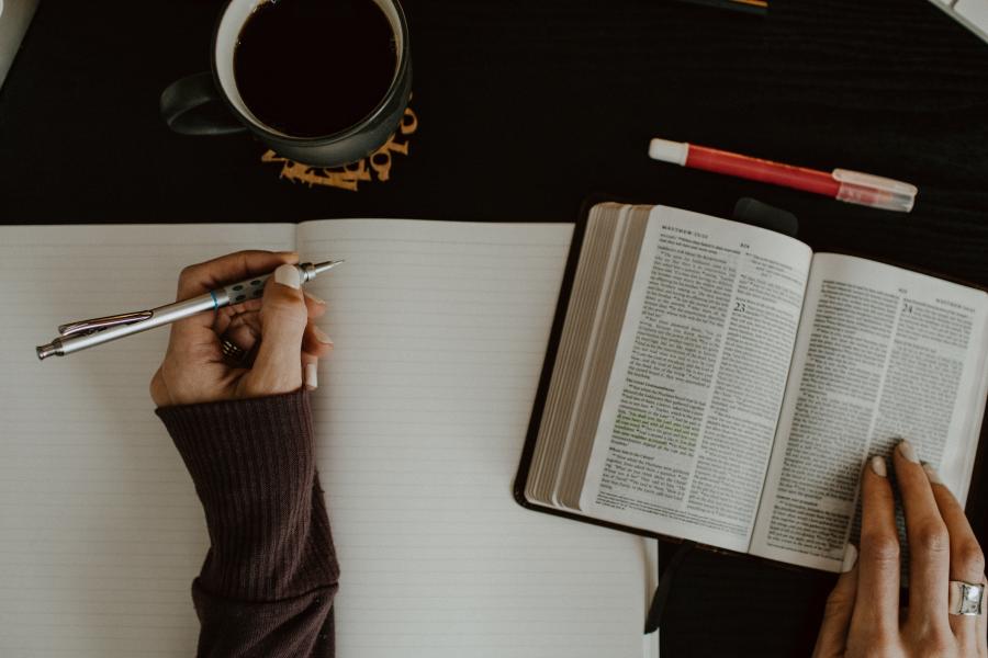 An image if a person reading a book and making notes