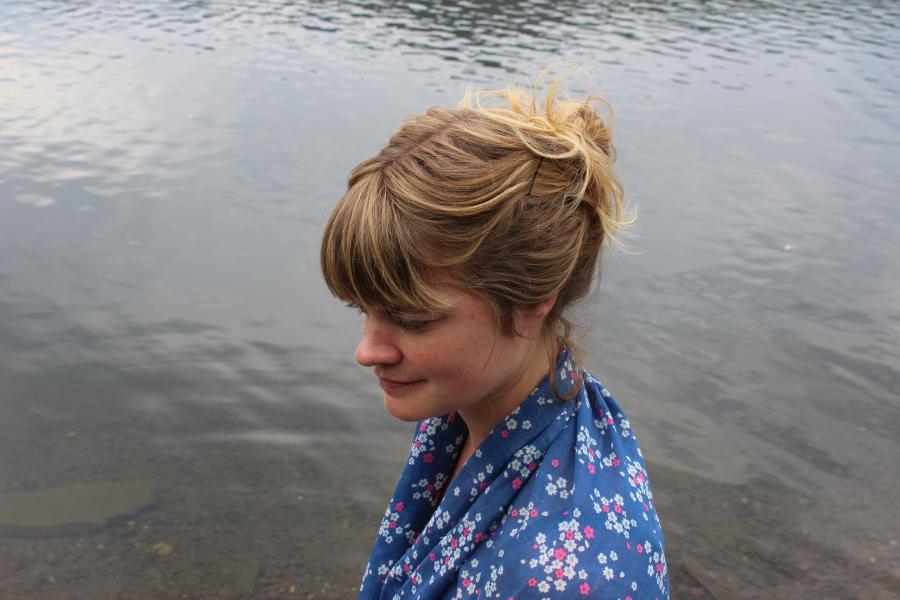 Headshot photograph of Alys Conran standing by the waterside