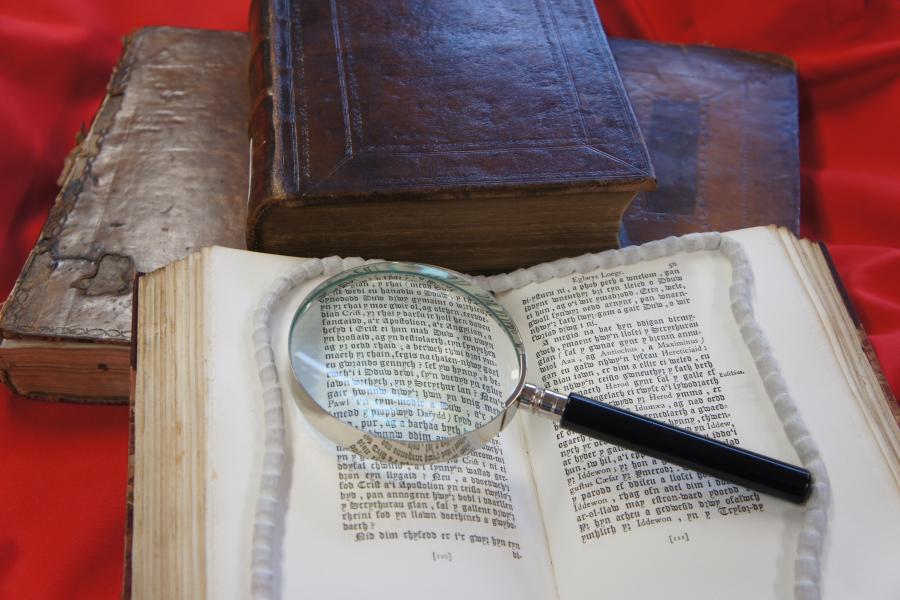 Photo of a pile of old books and a magnifying glass