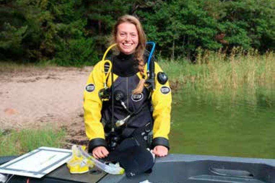 Ocean Sciences graduate, Charlotte Angove, in diving equipment on the shore of a lake