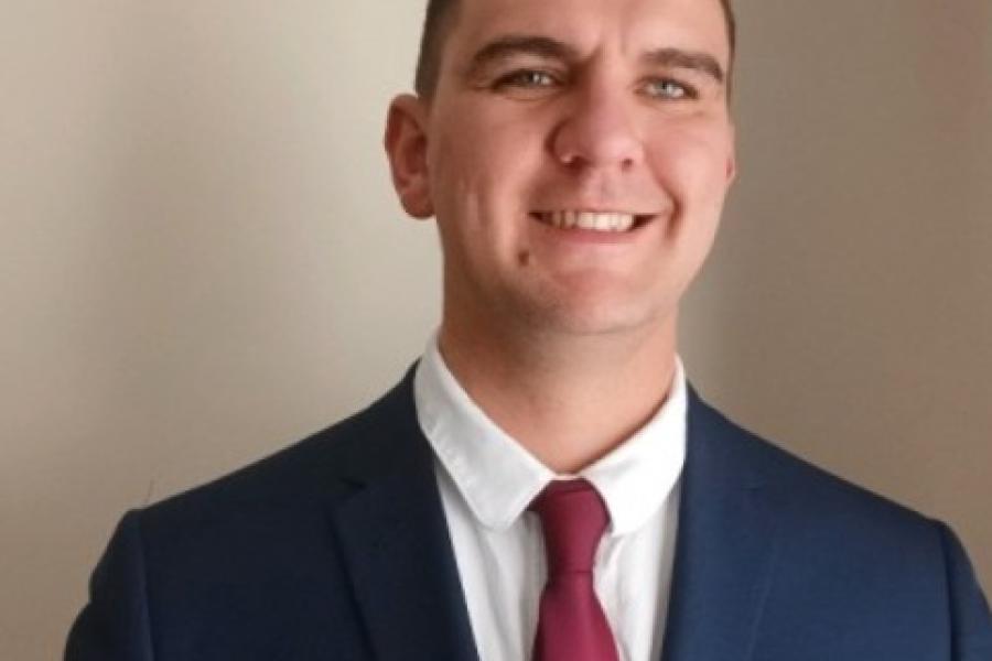  Joshua Roberts smiling to camera dressed in a suit