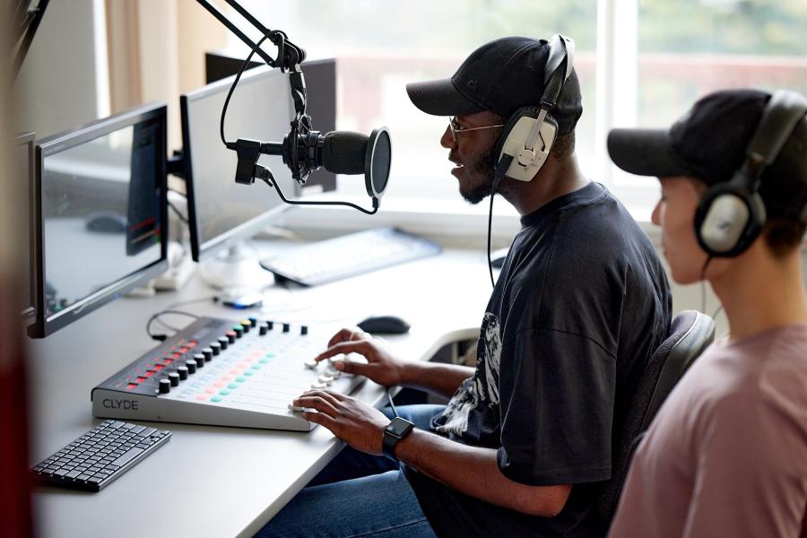 Two students sitting at a desk using podcast recoding equipment
