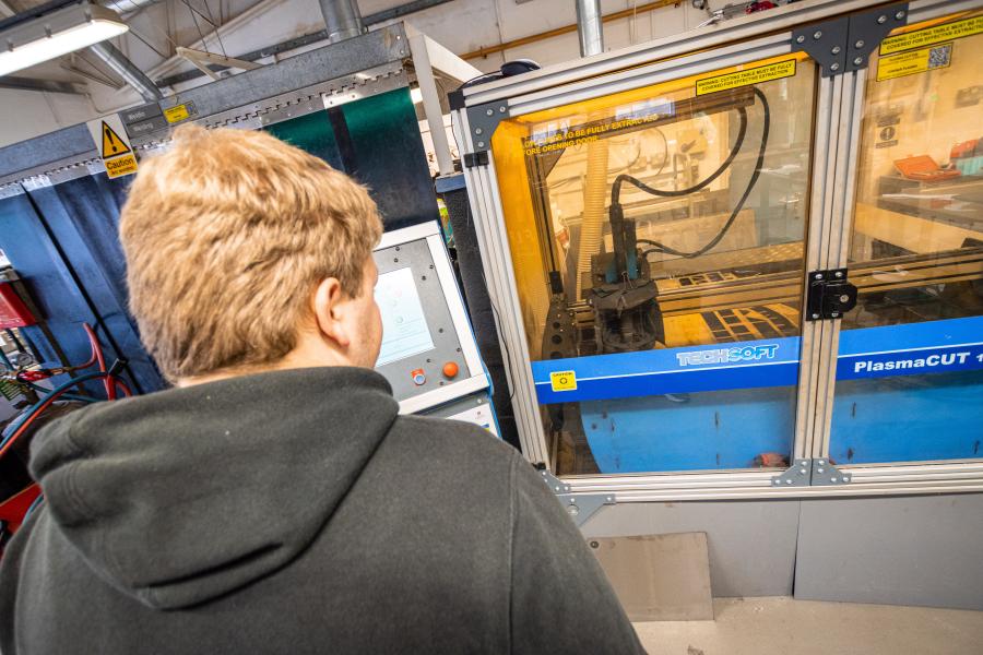 Student watching a plasma cutter cutting steel.