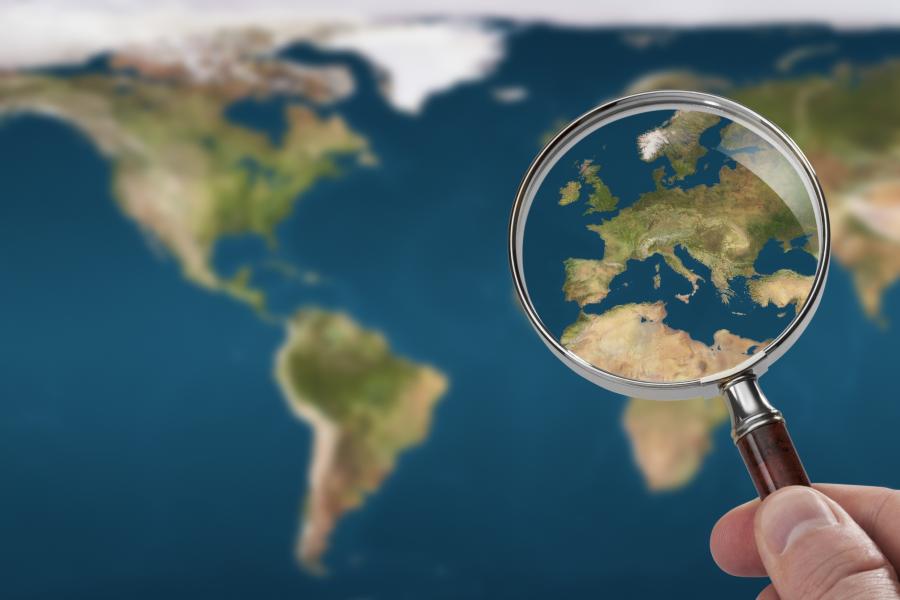 A map of the world with a magnifying glass lookig closer at Europe