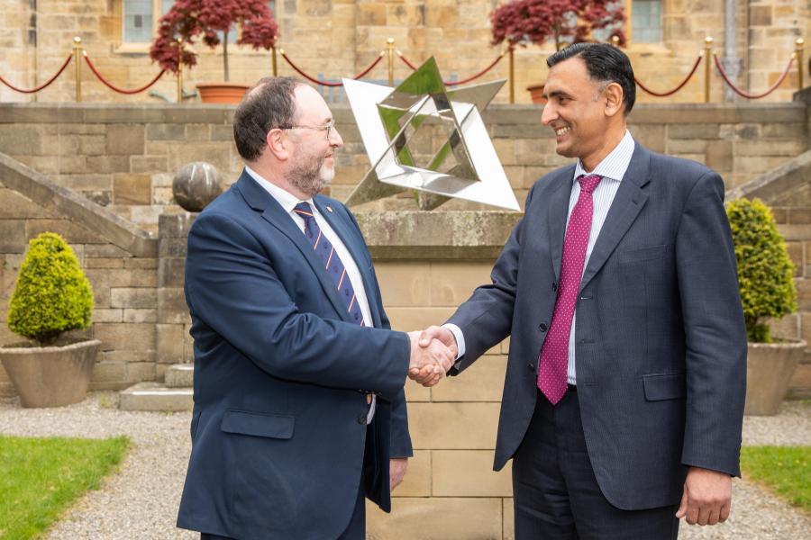 Two people shaking hands in front of a courtyard