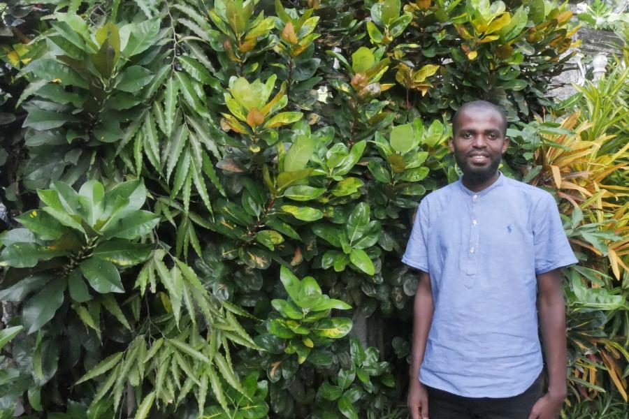 Picture of Abdoulkader Fardane, member of Dahari staff, standing in front of greenery