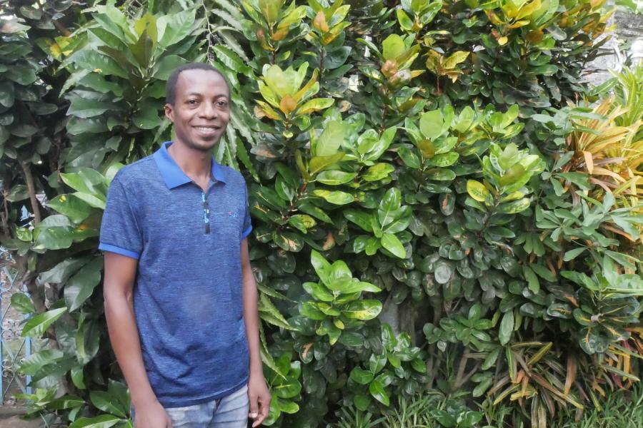 Amelaid Houmadi, member of Dahari staff, standing in front of greenery