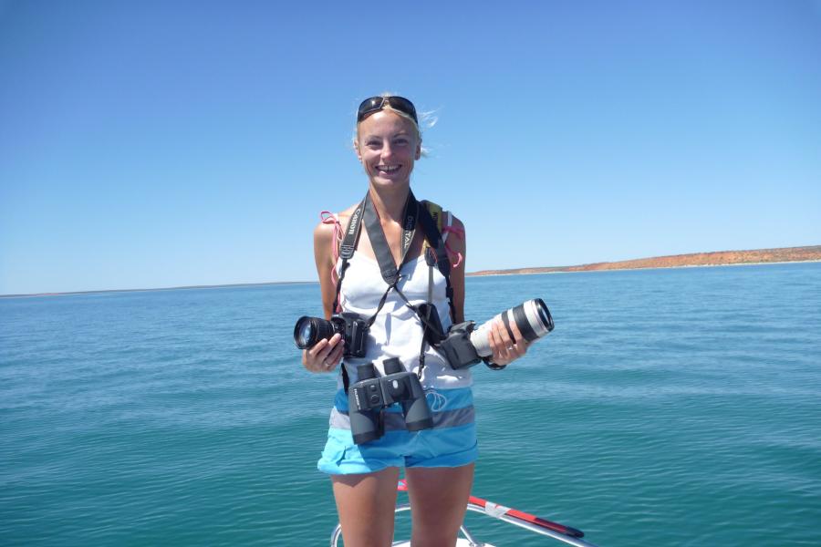 Image of member of staff, Ewa Krzyszczyk, standing in a boat holding cameras