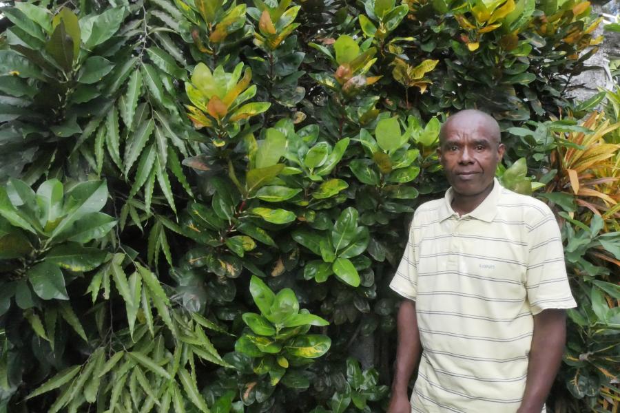 Image of member of Dahari staff, Ishaka Said standing in front of greenery