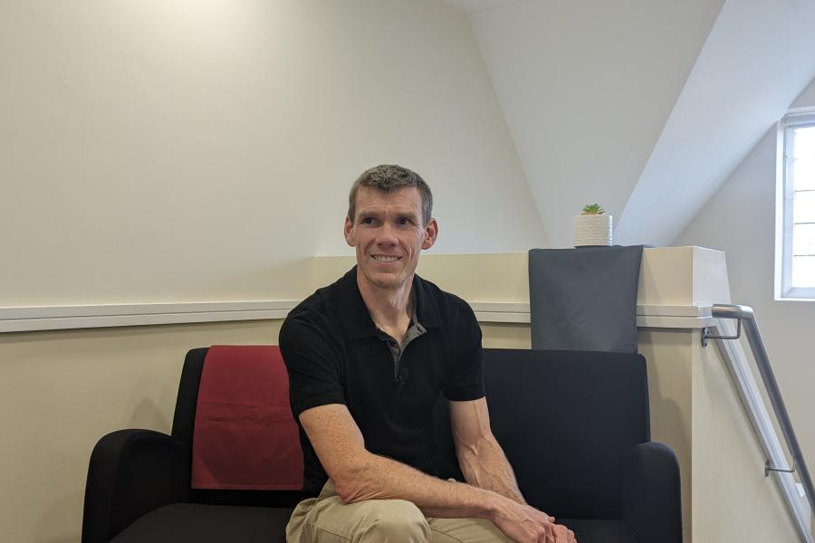 Dr Rhys ap Gwilym yn gwenu i'r camera