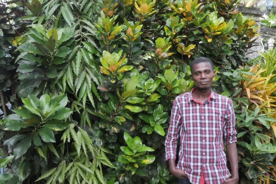 Member of Dahari staff, Samirou Soulaimana, standing in front of greenery