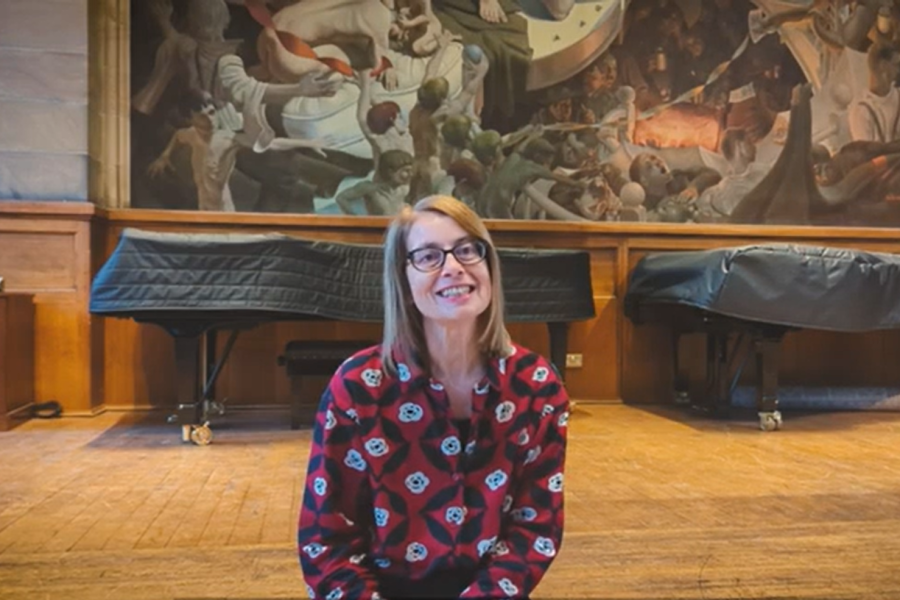Prof Doris Merkl Davies smiling to camera sitting on the stage in Powis hall