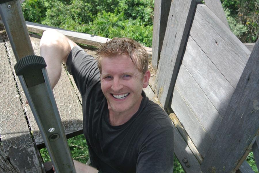 Man climbing to viewing tower, surrounded by trees