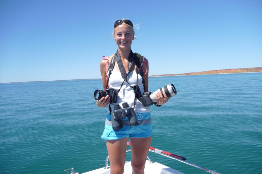 Lady standing holding cameras on a boat in the sea