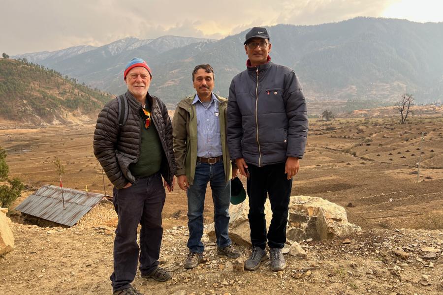 tri person yn sefyll mewn  tirlun sych yn Nepal.