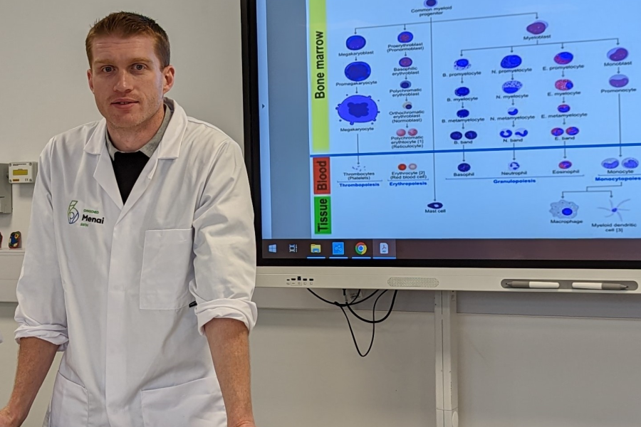 Luke Hughes in laboratory standing in front of large computer display screen 