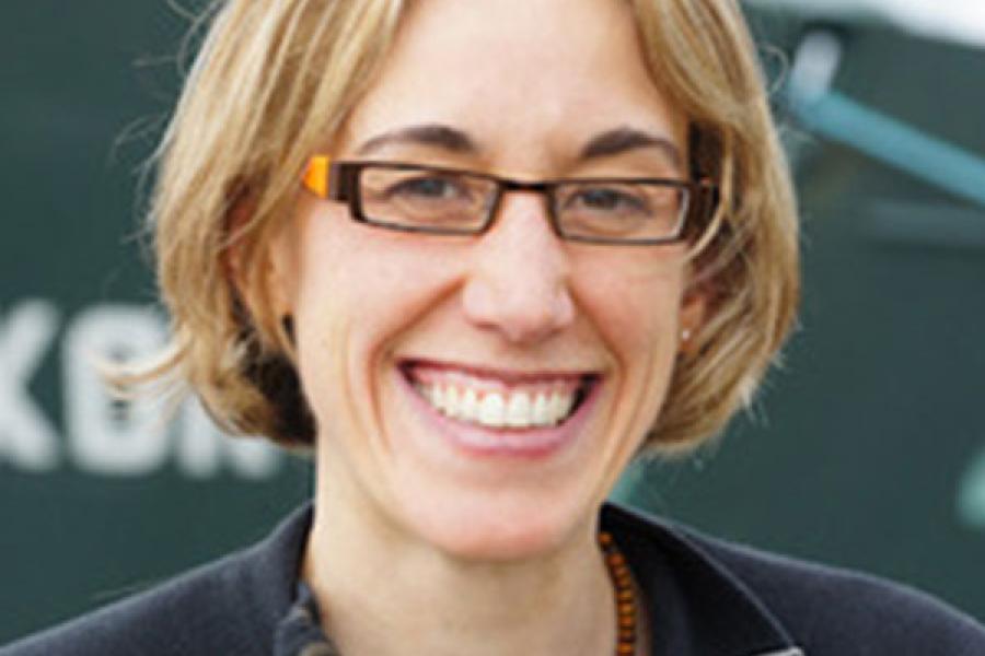 Smiling woman with short blonde hair in a bob and glasses.