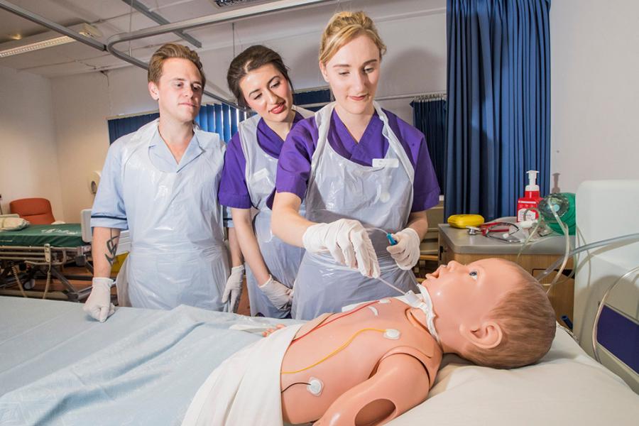 Three students in a hospital ward with a dummy patient