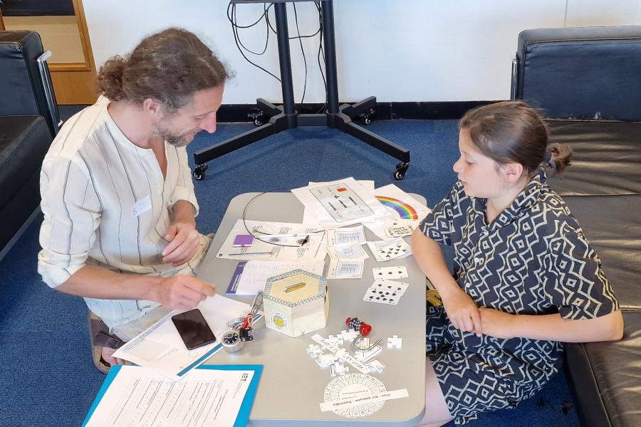 Man and child looking at a table containing various cards and activities.